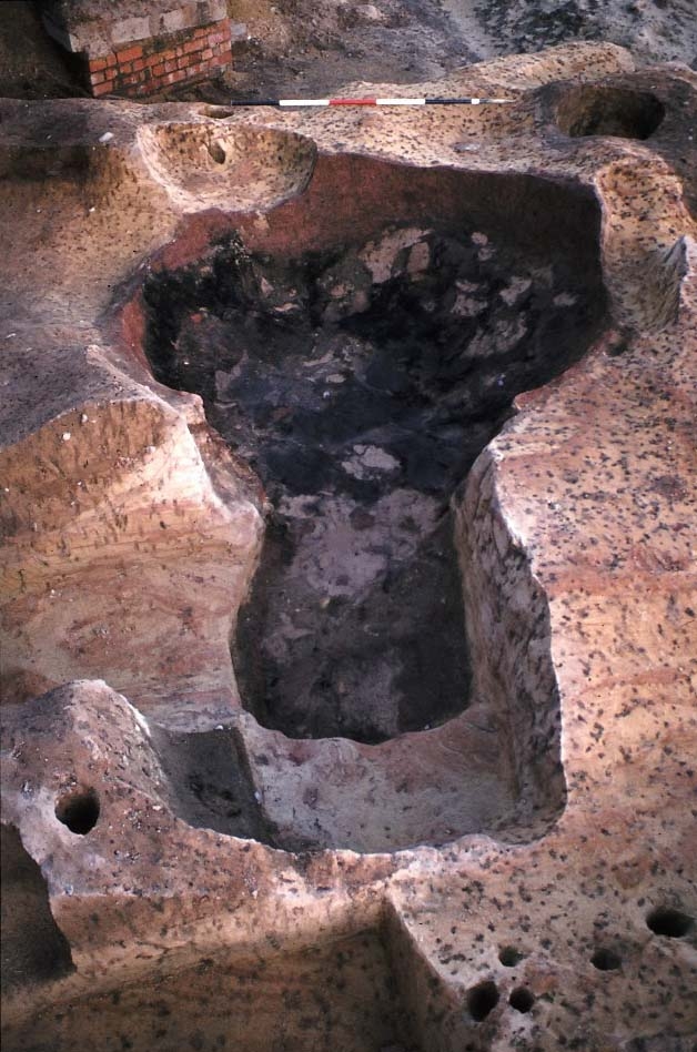 A photo of an archaeological excavation, showing post holes and a large area of burnt material.