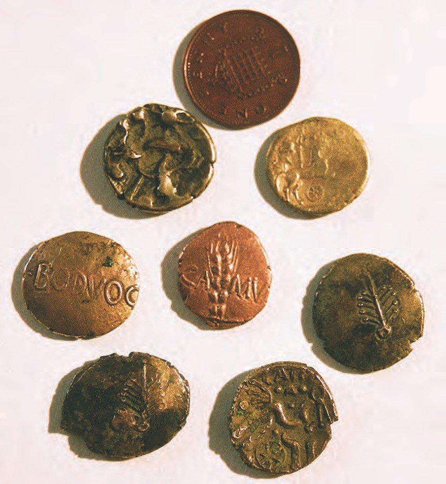 Collection of 7 Iron Age gold coins with a modern penny of similar size for comparison.