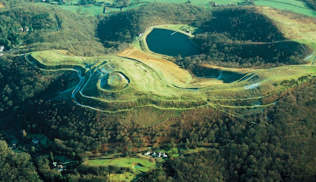 Aerial photograph of a Iron Age hillfort on the top of a hill surrounded by trees.