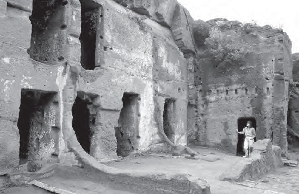 Photograph of woman standing in the doorway of a cave house.